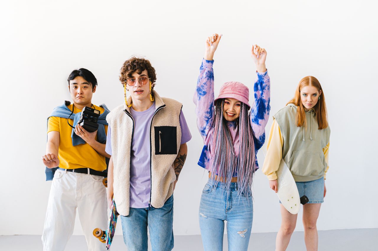 A stylish and diverse group of young adults posing with skateboards in a studio setting.