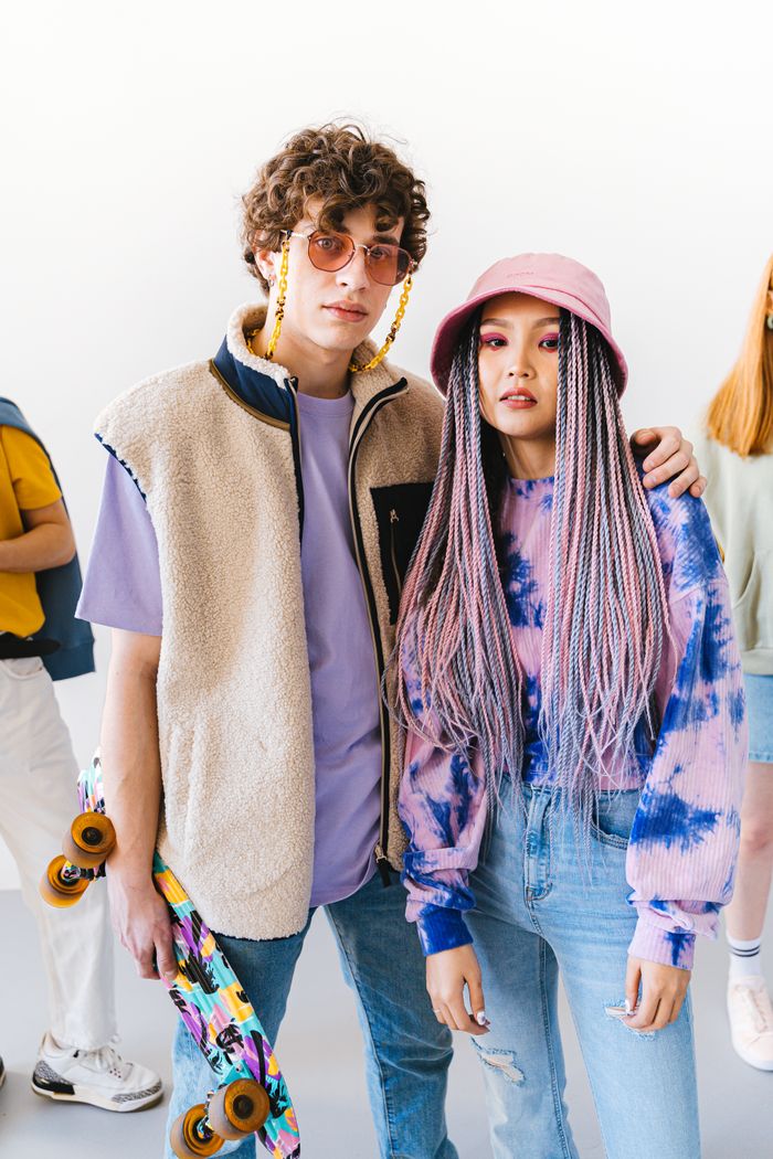 Fashionable young couple posing in casual attire with a skateboard. Trendy urban vibe.