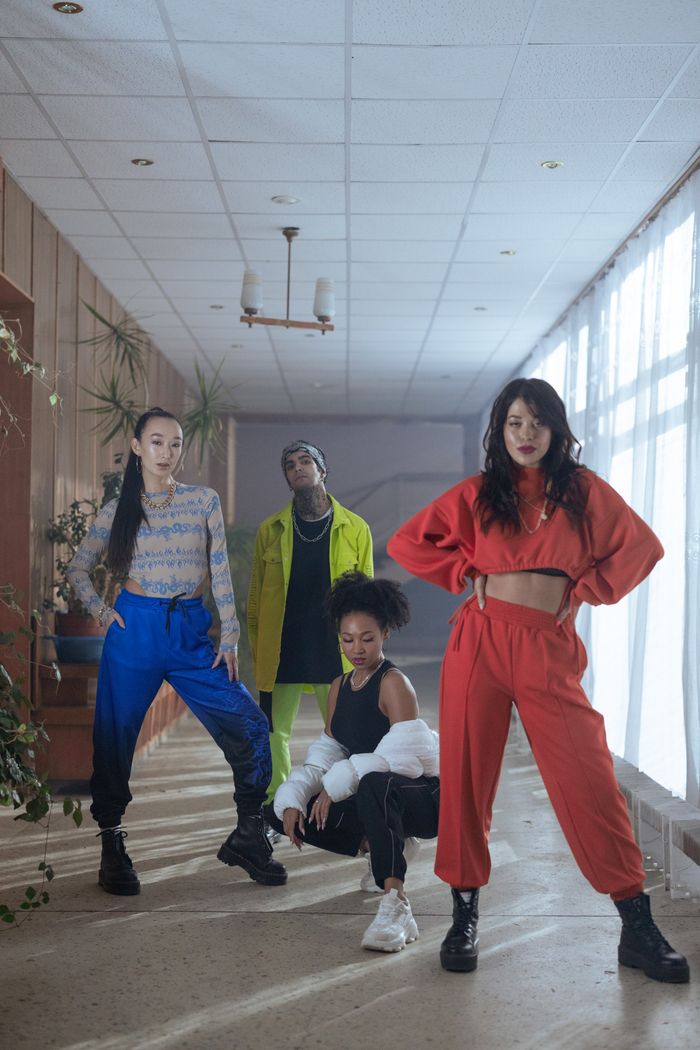 Fashionable group of diverse models showcasing bold outfits in a bright indoor setting.