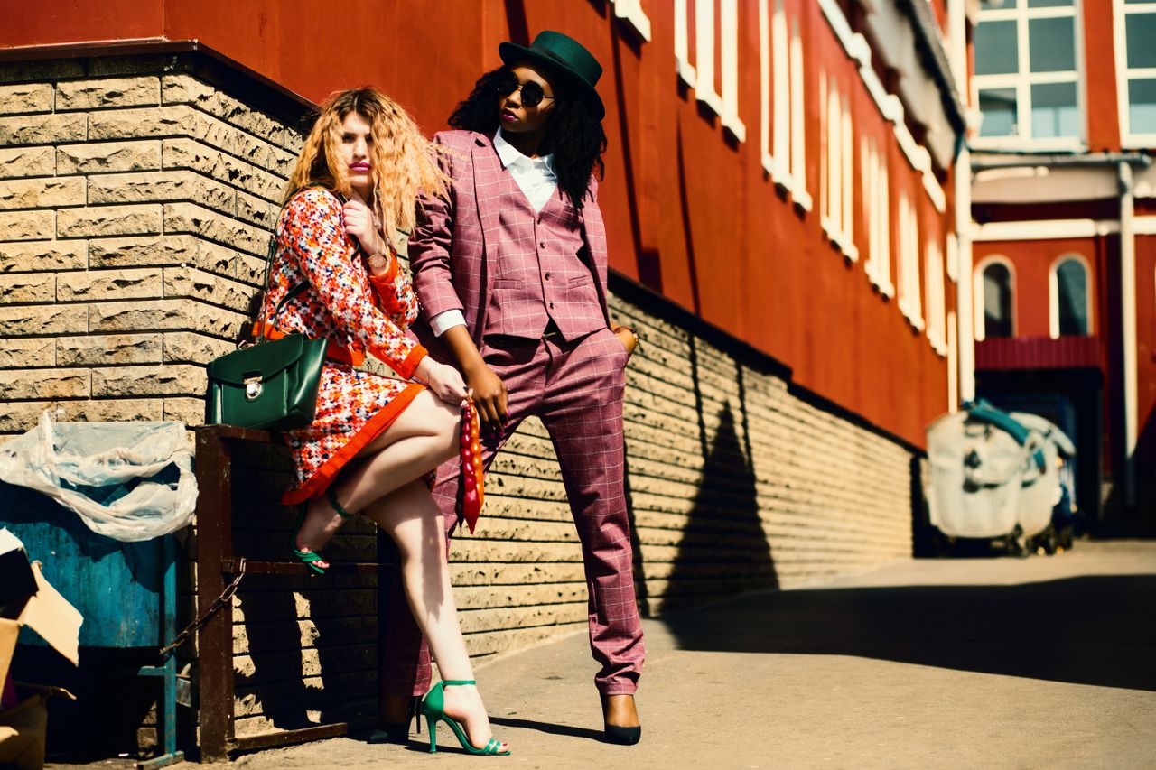 gallery-02 Fashionable duo posing outdoors in vibrant outfits, embracing urban style and confidence.